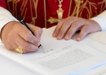 Close-up of hands of Pope Leo as he signs encyclical "Magnifica Humanitas."