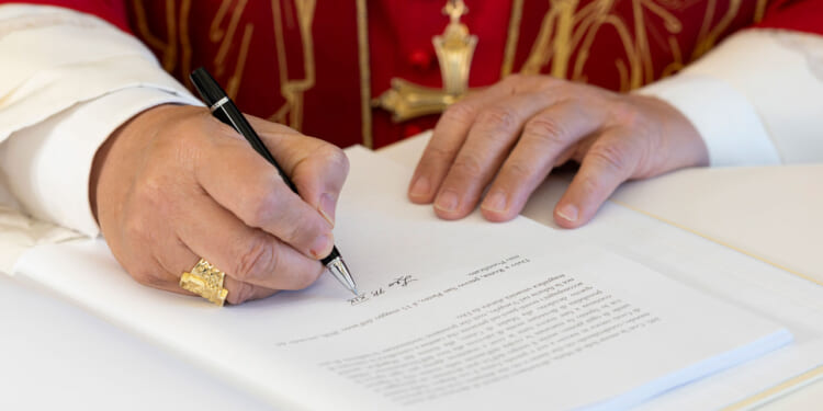 Close-up of hands of Pope Leo as he signs encyclical "Magnifica Humanitas."