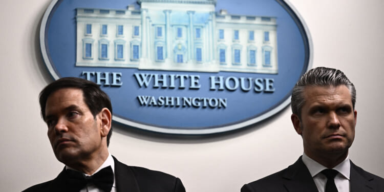 A stern looking Marco Rubio and Pete Hegseth stand together in White House briefing room.