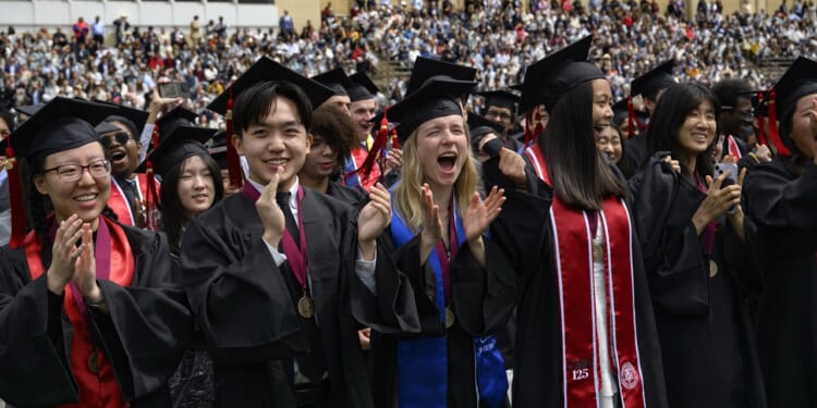 Graduates in robes clapping, cheering, and smiling