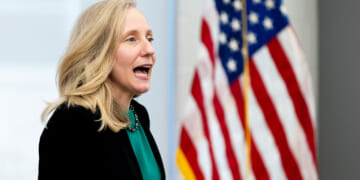 Abigail Spanberger with her mouth open, American flag in the background.