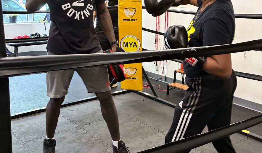 Midtown Youth Academy Executive Director Gloria Lee spars with UFC fighter Randy Brown at an event Wednesday, June 10, 2026, in Washington. (AP Photo/Fatima Hussein)