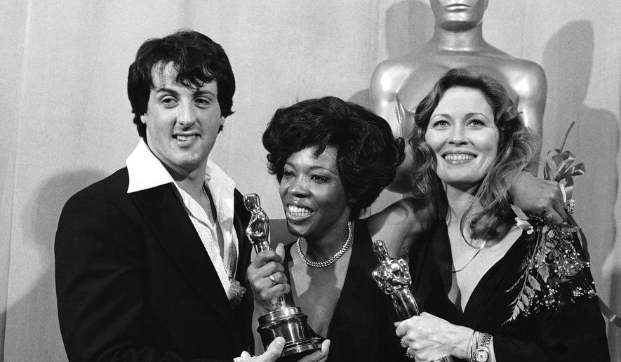 Actor and screenwriter Sylvester Stallone, left, poses with Eletha Finch, center, widow of actor Peter Finch, and actress Faye Dunaway at the Academy Awards in Los Angeles on March 28, 1977. (AP Photo/File)