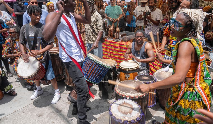 FILE - Drummers form a circle around Sika Dwimfo, better known as the, "Godfather of Leimert Park," during the neighborhood's Juneteenth celebration, June 19, 2024, at Leimert Park in Los Angeles. (AP Photo/Damian Dovarganes, File)