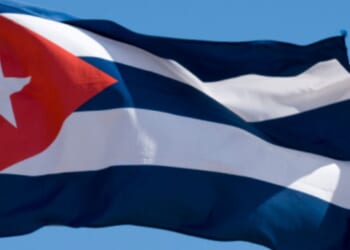 Cuban flag flies in the blue skies.