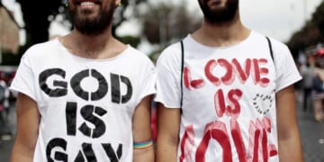 Men wearing shirts that say "God is gay" and "Love is love"