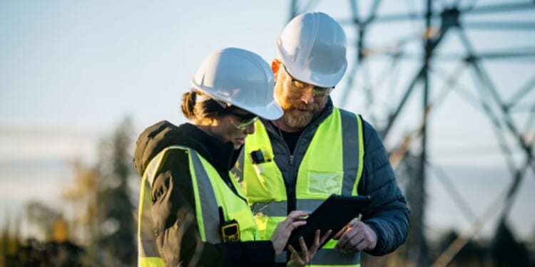A man and a woman stand at a utility center as they stare at a tablet.