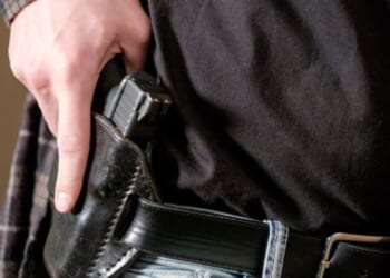 A man begins to pull a gun from his holster.