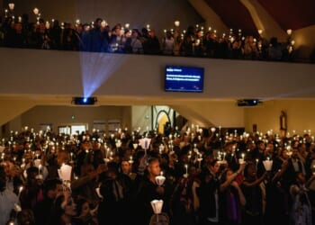 Christians hold candles during worship in a church in Lyon, France, on April 4, 2026.