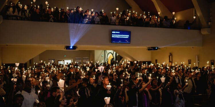Christians hold candles during worship in a church in Lyon, France, on April 4, 2026.