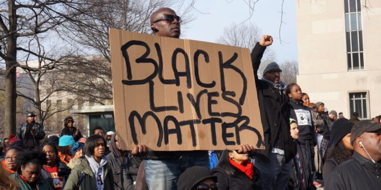 Racial activist protesters hold up a Black Lives Matter sign on Pennsylvania Avenue in Washington on Dec. 13, 2014.