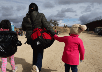 An immigrant and her two daughters walk along the U.S. Mexico Border.