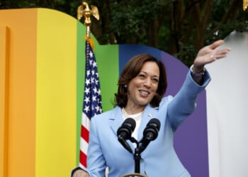 Kamala Harris waves in front of a backdrop of LGBT pride colors.