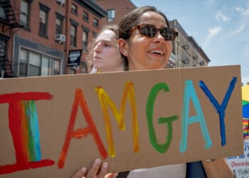 Woman holding a sign that says "I am gay"