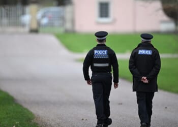 Police officers approach the gates of the Royal Lodge, Andrew Mountbatten-Windsor's former residence in Windsor Great Park, on Feb. 20, 2026, in Windsor, England.