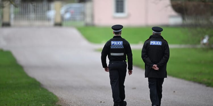 Police officers approach the gates of the Royal Lodge, Andrew Mountbatten-Windsor's former residence in Windsor Great Park, on Feb. 20, 2026, in Windsor, England.