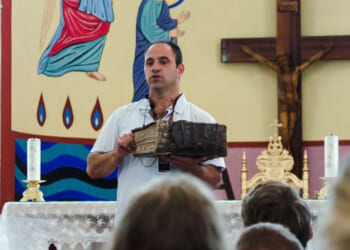 Shadi Khalloul presents an ancient Aramean Bible while speaking to a group of students at the Syriac Maronite Church of Antioch in Jish.