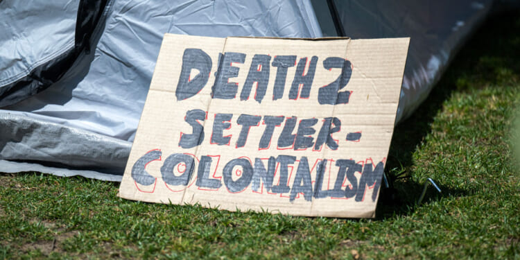 A Gaza solidarity encampment sign reads 'Death to Settler Colonialism.'