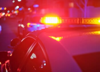 Police car lights flash on a road.