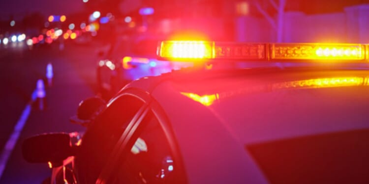 Police car lights flash on a road.