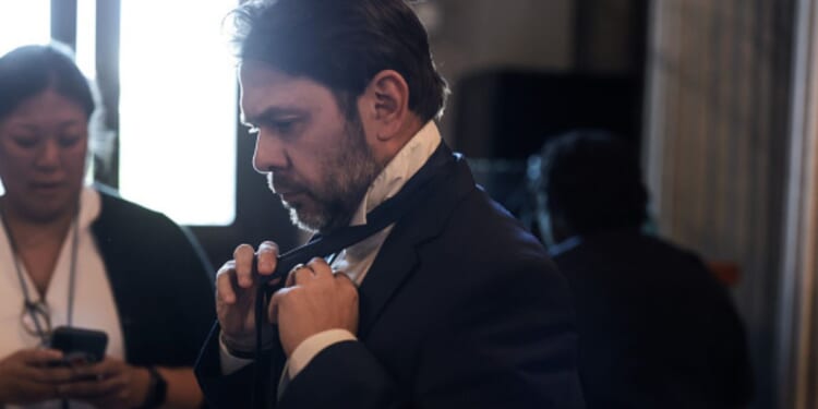 Senator Ruben Gallego ties his tie as he walks to the Senate Chambers on May 11, 2026.