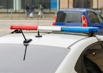 A police car with flashing lights is pictured in a stock photo. 
