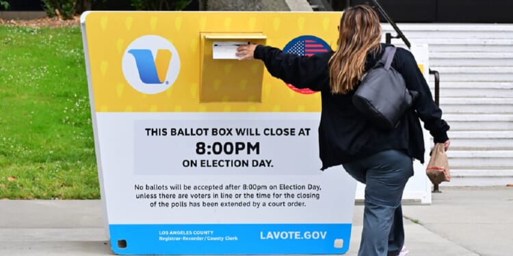 A voter drops a ballot in a drop box Monday at the Los Angeles County Registrar during early voting in the state's primary election.