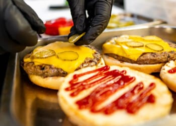 Close-up of hands assembling a fast food burger.