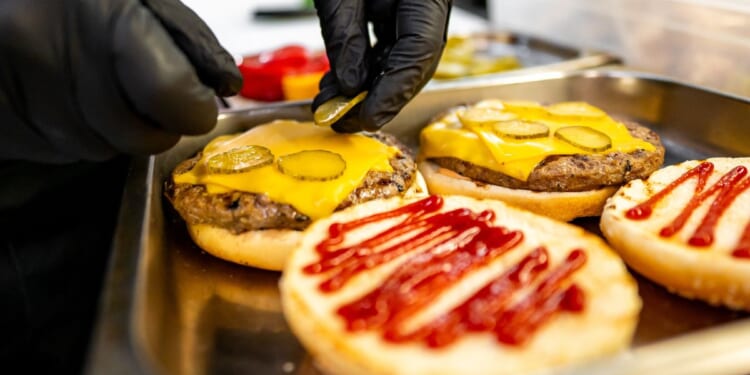 Close-up of hands assembling a fast food burger.