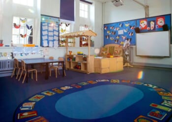 An image of an empty nursery classroom with a rug in the middle of the floor.