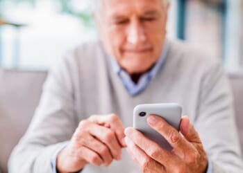 An elderly man looks at his phone.