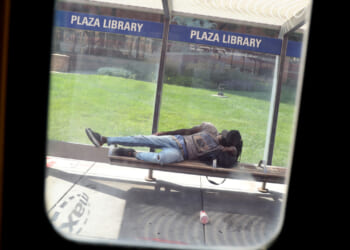 A bus window frames a person napping on the Plaza Library bench. The Kansas City Area Transportation Authority (KCATA) bus is free for all riders. (Photo by Pat Greenhouse/The Boston Globe via Getty Images)