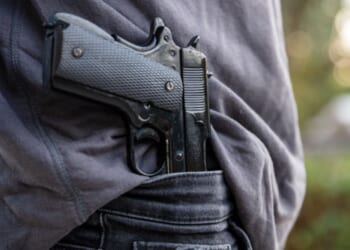 Man carries gun in his pants as he walks in a field.
