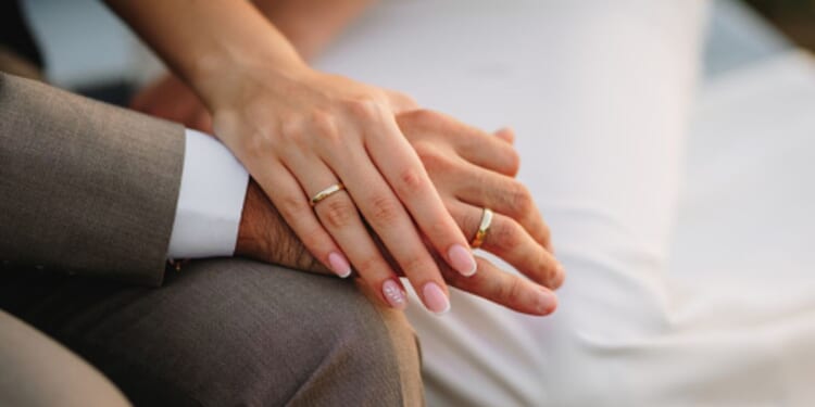 A groom and a bride hold hands.