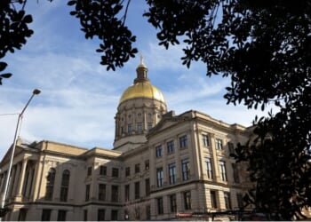 The Georgia State Capitol Building is shown among trees.