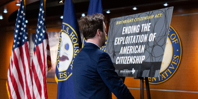 A congressional staffer sets up a posted on stage for Rep. Brian Babin's news conference on the Birthright Citizenship Act in the U.S. .Capitol on Thursday, January 23, 2025.