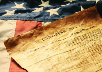 The Declaration of Independence laying upon an old American flag.