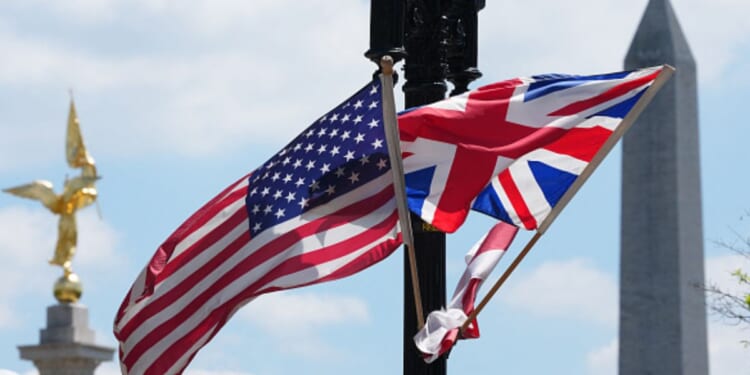 The United States flag and United Kingdom flag wave together on a light pole.