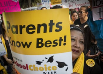A woman holding a sign that says "Parents know best! School Choice Week"
