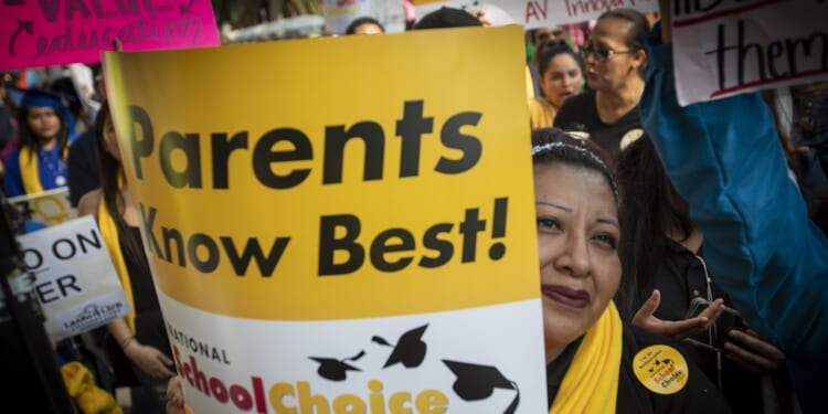 A woman holding a sign that says "Parents know best! School Choice Week"