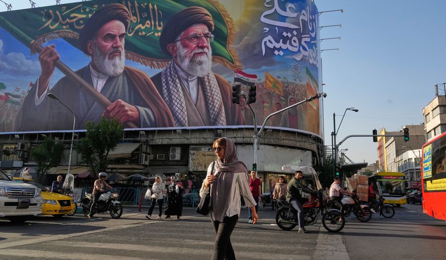 People walk under a banner showing portraits of the late revolutionary founder Ayatollah Khomeini, left, and the slain Supreme Leader Ayatollah Ali Khamenei, who was killed in U.S. and Israeli strikes on Feb. 28, in Tehran, Iran, Saturday, June 6, 2026. (AP Photo/Vahid Salemi) ** FILE **
