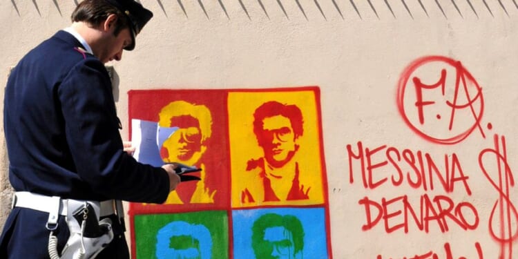 An Italian officer takes notes on graffiti of Matteo Messini Denaro on April 24, 2008.