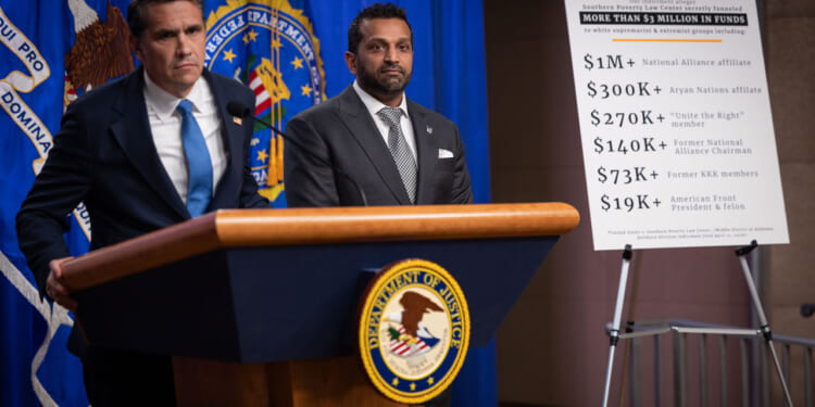 Todd Blanche at a podium with Kash Patel at his side as they announce charges against SPLC.