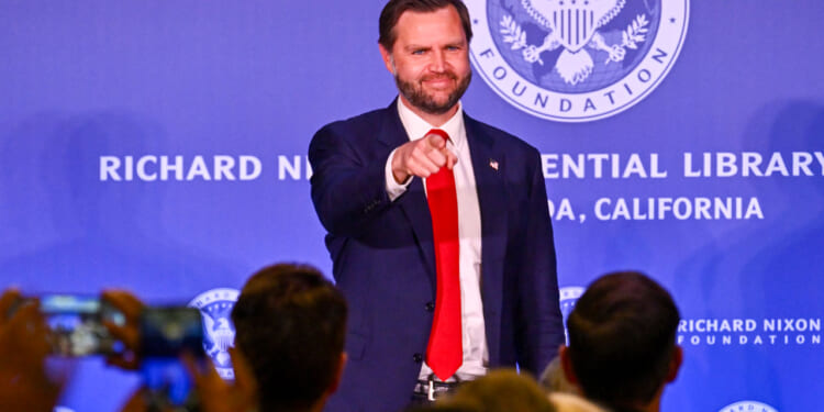JD Vance in blue jacket and red tie points into the audience with a smile at the Richard Nixon Presidential Library.
