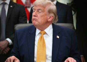 A frowning President Trump sits at his Oval Office desk.