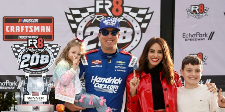 Kyle Busch, driver of the HendrickCars.com Chevrolet, celebrates with his children and wife, Samantha Busch, in victory lane after winning the NASCAR Craftsman Truck Series Fr8 Racing 208 at Echo Park Speedway on Feb. 21, 2026, in Hampton, Georgia.