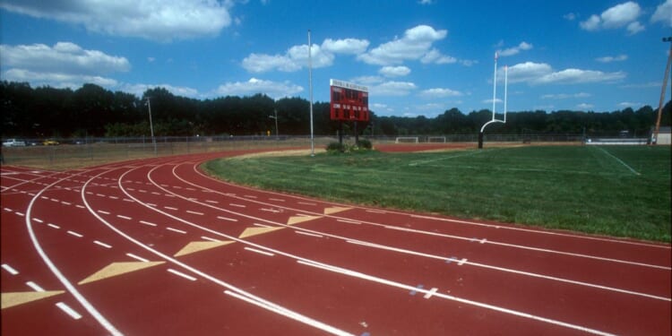 A high school running track and field with a goal post.