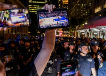 A Knicks fan holds up a screen of the NBA finals game between New York City and San Antonio at a watch party in Bryant Park for Game 3 of the Finals in New York City on June 8, 2026.