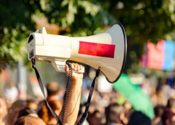 A protestor raises a megaphone amongst a crowd.