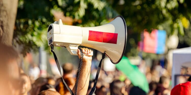 A protestor raises a megaphone amongst a crowd.